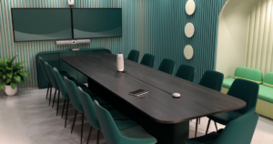 Modern conference room with a long dark wood table, teal chairs, and wall-mounted screens in teal-striped decor.