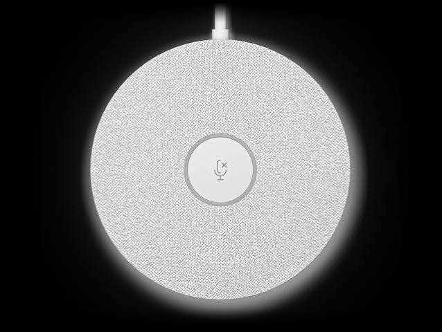 Round smart speaker with a textured white surface, top power cable, and a centered muted microphone icon.