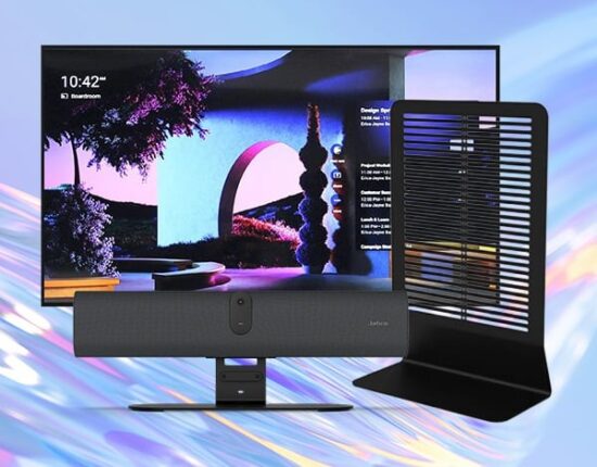 Desktop computer setup with a large monitor displaying colorful wallpaper, a soundbar with a central webcam in front, and a tall freestanding vented device on the right.